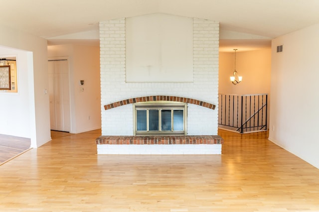 1723 Teton Ln NE, Rochester, MN 55906 - unfurnished living room with lofted ceiling, light wood-style floors, a chandelier, a brick fireplace, and baseboards
