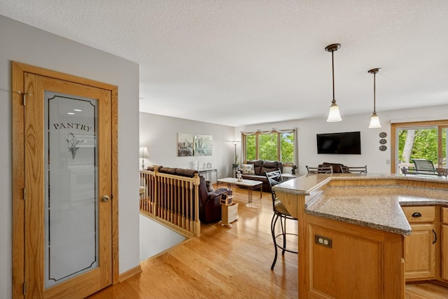 1301 Crestridge Ln, Eagan, MN 55123 - kitchen featuring healthy amount of natural light, light wood-style floors, pendant lighting, and light stone counters