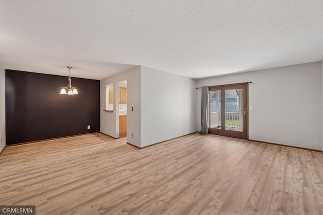 7475 110th St W, Bloomington, MN 55438 - spare room with light wood finished floors, a chandelier, a textured ceiling, and baseboards