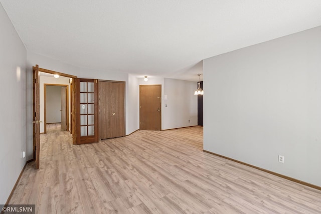 7475 110th St W, Bloomington, MN 55438 - spare room featuring light wood-style flooring, baseboards, and a chandelier