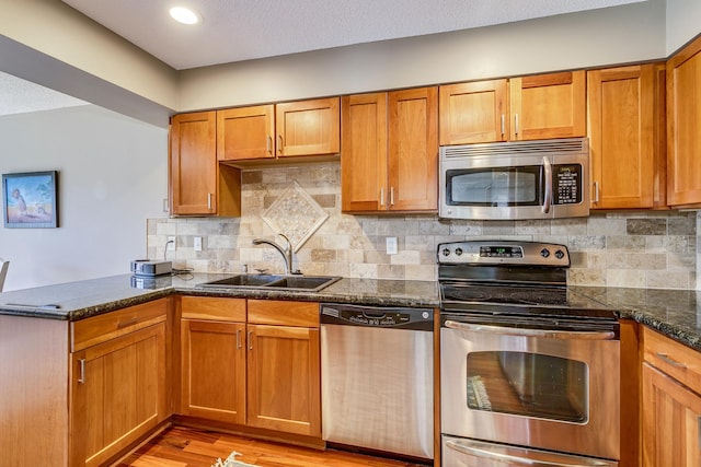 1709 140th St, Burnsville, MN 55337 - kitchen featuring stainless steel appliances, a sink, a peninsula, brown cabinetry, and backsplash