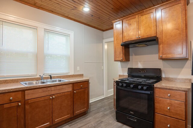 kitchen featuring black range with gas stovetop, under cabinet range hood, a sink, wood finished floors, and wood ceiling