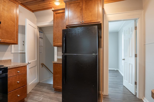 kitchen featuring black appliances, wood finished floors, brown cabinetry, and light countertops