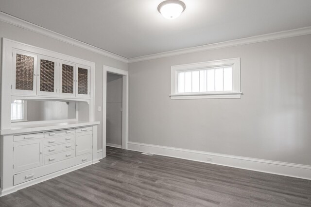 spare room with dark wood-style floors, ornamental molding, and baseboards