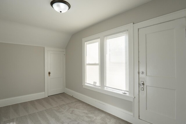 additional living space with vaulted ceiling, light carpet, baseboards, and plenty of natural light