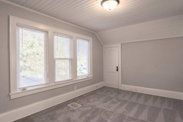 empty room featuring plenty of natural light, carpet floors, vaulted ceiling, and baseboards
