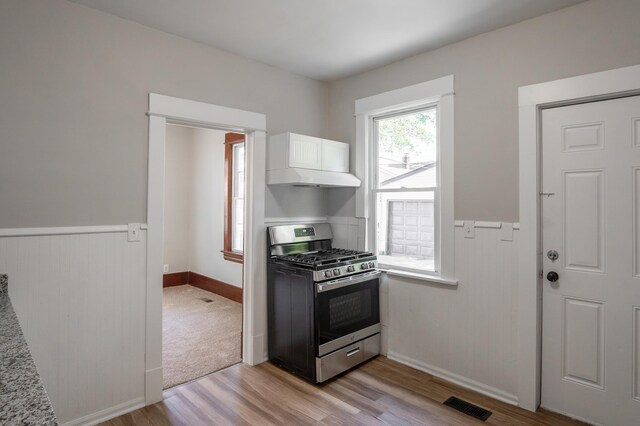 188 Wyoming St E, Saint Paul, MN 55107 - kitchen with stainless steel gas stove, light wood-style floors, white cabinetry, wainscoting, and baseboards