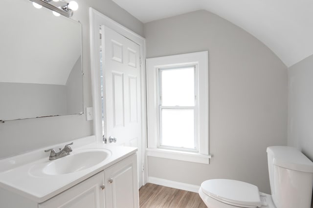 188 Wyoming St E, Saint Paul, MN 55107 - half bath with lofted ceiling, toilet, vanity, wood finished floors, and baseboards