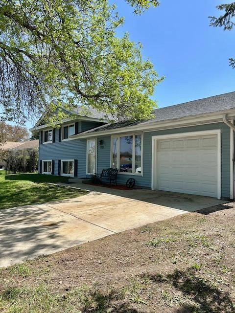 split level home with an attached garage, driveway, and a front yard