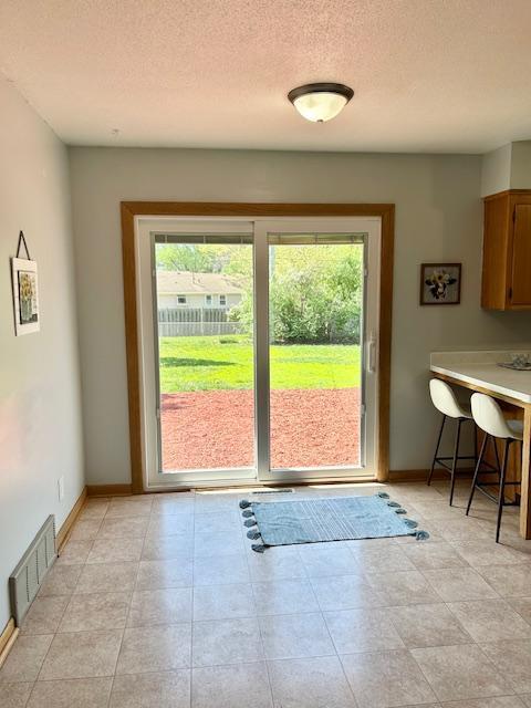 entryway with plenty of natural light, baseboards, a textured ceiling, and light tile patterned floors