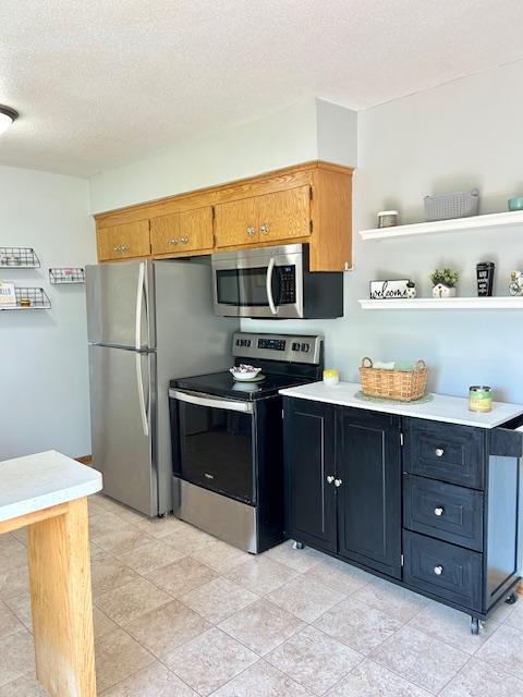 kitchen with stainless steel appliances, light countertops, a textured ceiling, and open shelves