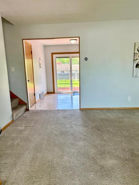spare room featuring carpet floors, baseboards, and stairway
