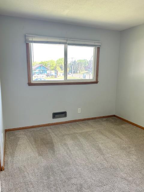 carpeted empty room featuring baseboards