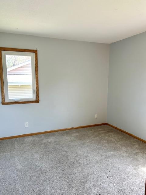carpeted spare room featuring baseboards
