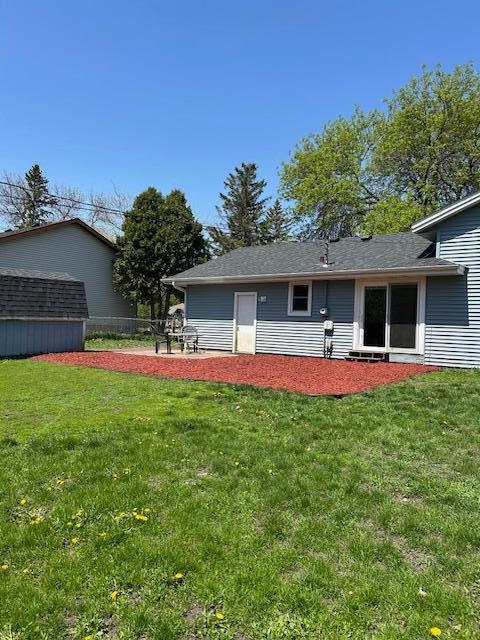 back of property featuring a yard, an outbuilding, and a storage unit