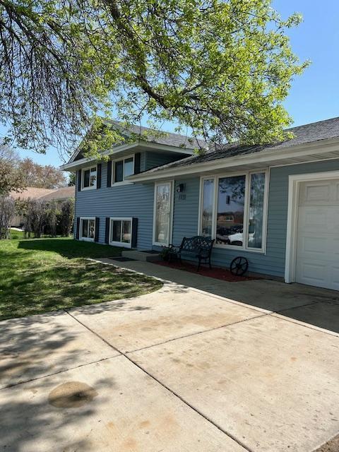 tri-level home with driveway, a front yard, and an attached garage