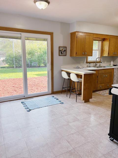 7731 80th St S, Cottage Grove, MN 55016 - kitchen with light countertops, brown cabinets, a peninsula, and a kitchen breakfast bar