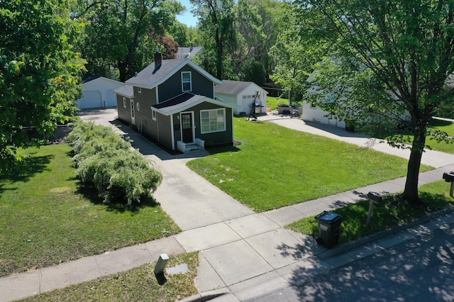 711 3rd St SE, Willmar, MN 56201 - view of front facade with a front yard, an outdoor structure, a chimney, and a detached garage