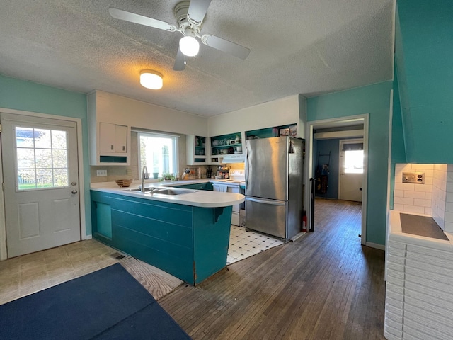 kitchen with freestanding refrigerator, a sink, white electric stove, a peninsula, and a textured ceiling
