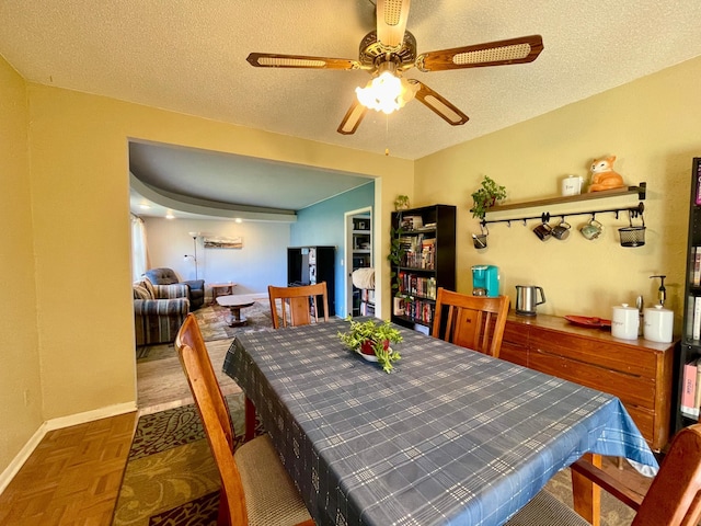 dining space with a ceiling fan, a textured ceiling, and baseboards