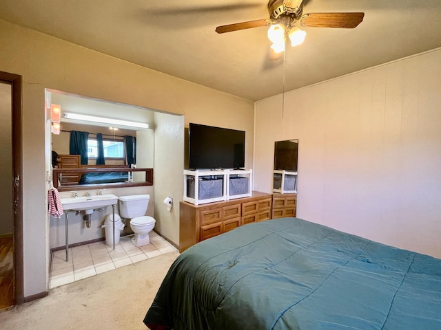 tiled bedroom featuring carpet floors, ensuite bath, and a ceiling fan