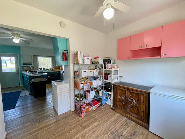 kitchen with a ceiling fan, wood finished floors, white refrigerator, and red cabinetry