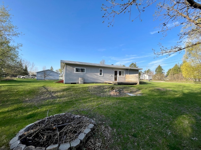 back of house featuring a wooden deck, a lawn, and a fire pit