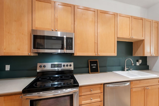 kitchen with appliances with stainless steel finishes, a sink, light brown cabinets, and light countertops