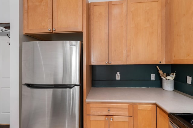 kitchen with freestanding refrigerator, light countertops, range, and light brown cabinets