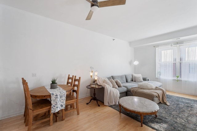 living room with light wood-type flooring, ceiling fan, and baseboards