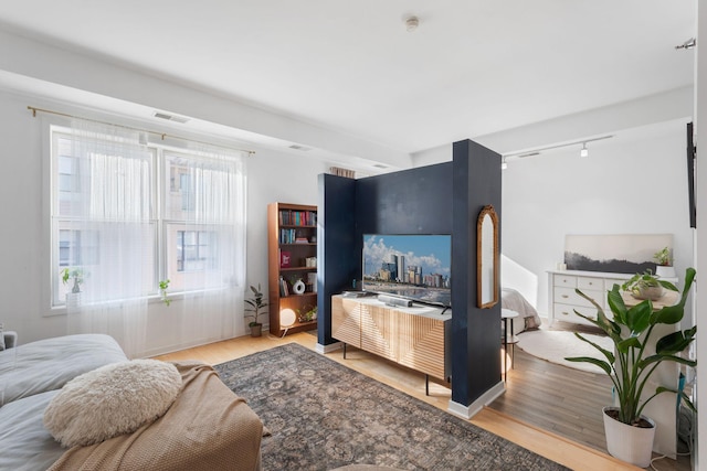 living area with rail lighting and wood finished floors