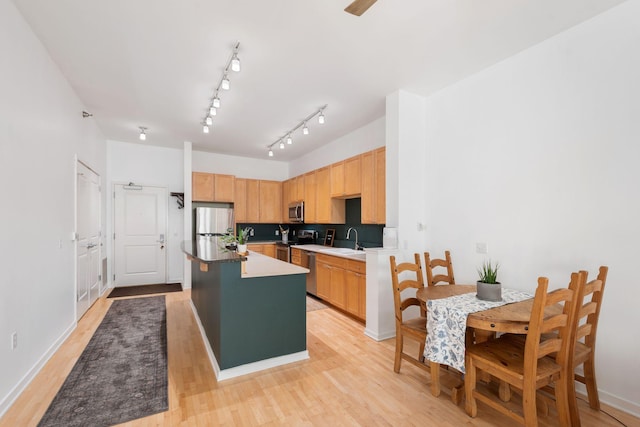 kitchen featuring a sink, stainless steel appliances, a kitchen island, light wood-style floors, and light brown cabinetry
