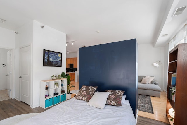 bedroom with wood finished floors and track lighting