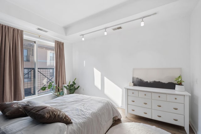 bedroom with rail lighting and wood finished floors