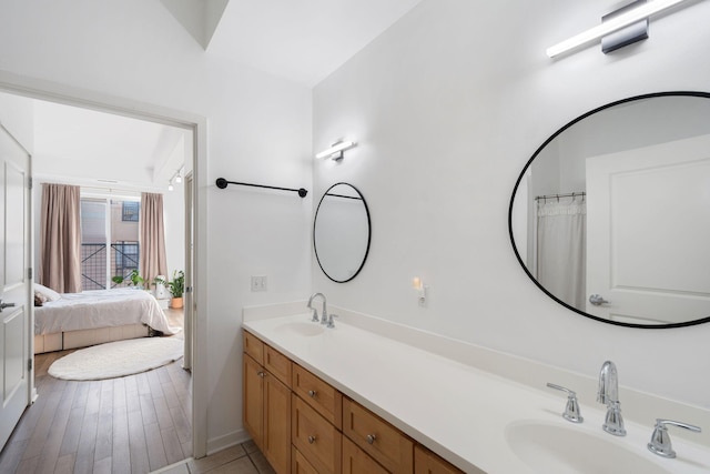 full bath featuring double vanity, connected bathroom, and baseboards