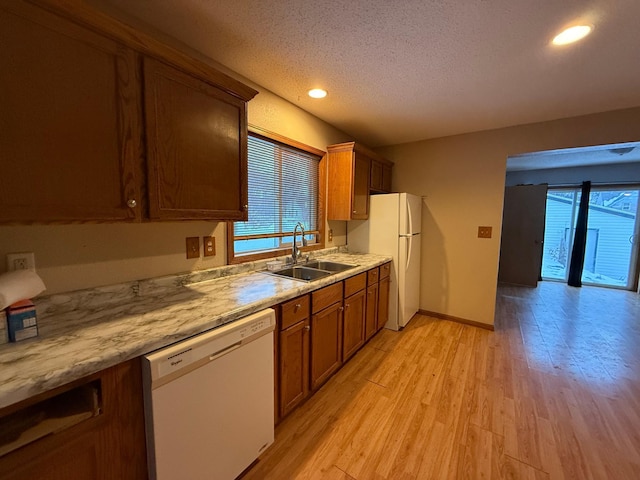122 7th St, Montevideo, MN 56265 - kitchen with white appliances, a sink, a textured ceiling, light wood finished floors, and brown cabinetry