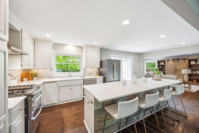 18120 Hummingbird Rd, Deephaven, MN 55391 - kitchen featuring appliances with stainless steel finishes, a sink, a kitchen breakfast bar, dark wood-style floors, and plenty of natural light