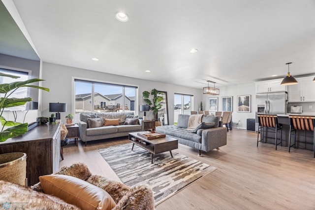 living room featuring healthy amount of natural light, light wood finished floors, recessed lighting, and a chandelier