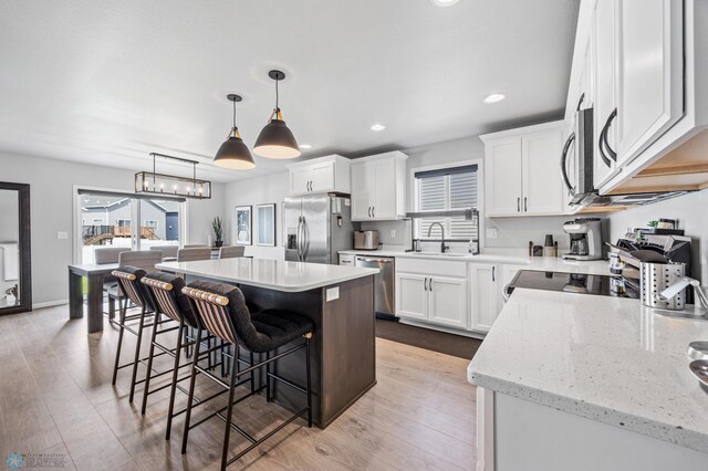 kitchen with stainless steel appliances, a sink, a kitchen bar, a kitchen island, and plenty of natural light