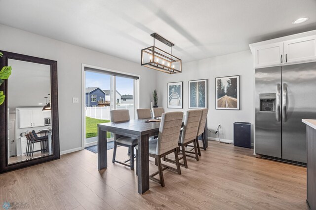 dining area with light wood-style flooring, baseboards, and a chandelier
