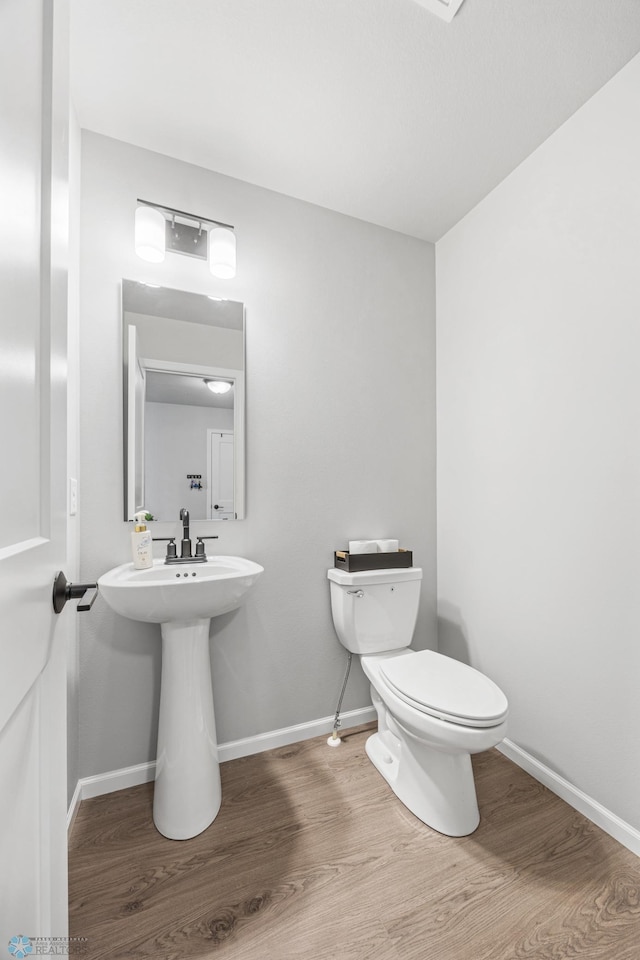 bathroom with wood finished floors, toilet, and baseboards