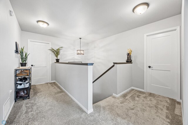corridor with an upstairs landing, carpet flooring, and baseboards