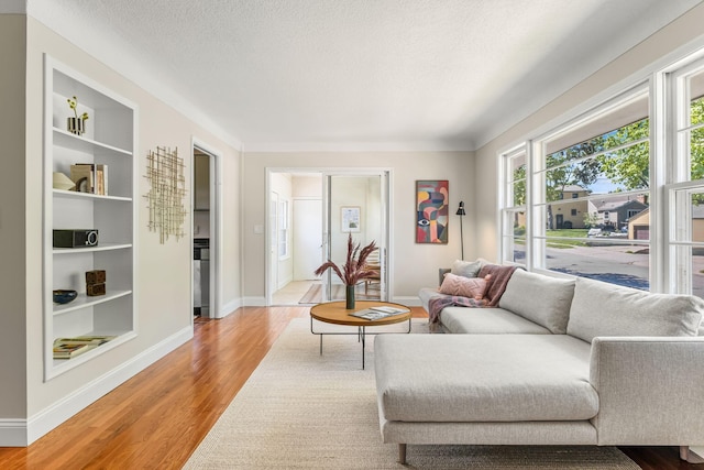 343 41st St, Minneapolis, MN 55409 - living area featuring built in shelves, light wood-style floors, a textured ceiling, and baseboards