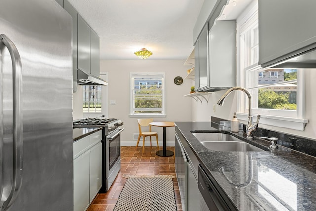 343 41st St, Minneapolis, MN 55409 - kitchen with stainless steel appliances, a sink, dark stone counters, exhaust hood, and baseboards