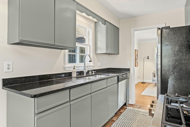 343 41st St, Minneapolis, MN 55409 - kitchen featuring stainless steel appliances, a sink, gray cabinets, dark stone counters, and baseboards
