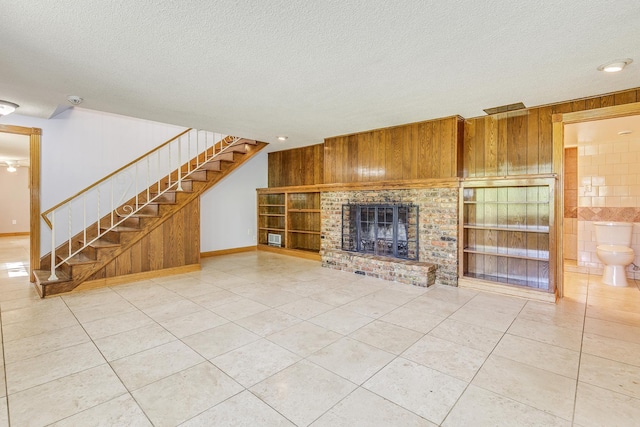 2000 191st Ave NW, Oak Grove, MN 55011 - unfurnished living room featuring wood walls, light tile patterned floors, stairway, a brick fireplace, and a textured ceiling