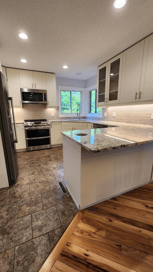2339 2nd Ave SW, Rochester, MN 55902 - kitchen with appliances with stainless steel finishes, backsplash, a sink, light stone countertops, and white cabinetry