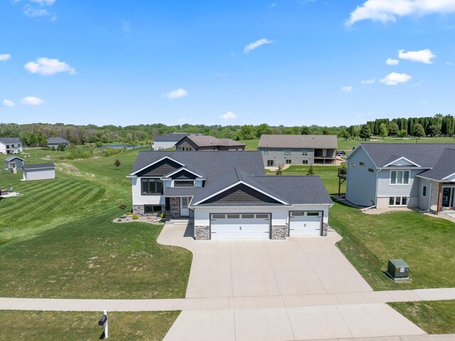 409 10th St NW, Dodge Center, MN 55927 - view of front of home featuring an attached garage, driveway, stone siding, a front yard, and a residential view