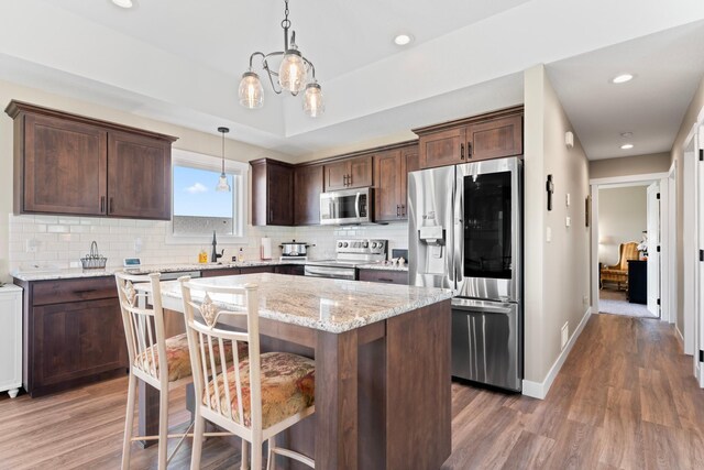 409 10th St NW, Dodge Center, MN 55927 - kitchen featuring appliances with stainless steel finishes, wood finished floors, dark brown cabinetry, a kitchen island, and recessed lighting