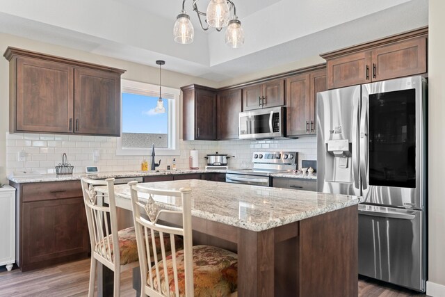 409 10th St NW, Dodge Center, MN 55927 - kitchen featuring appliances with stainless steel finishes, wood finished floors, dark brown cabinets, and a kitchen island